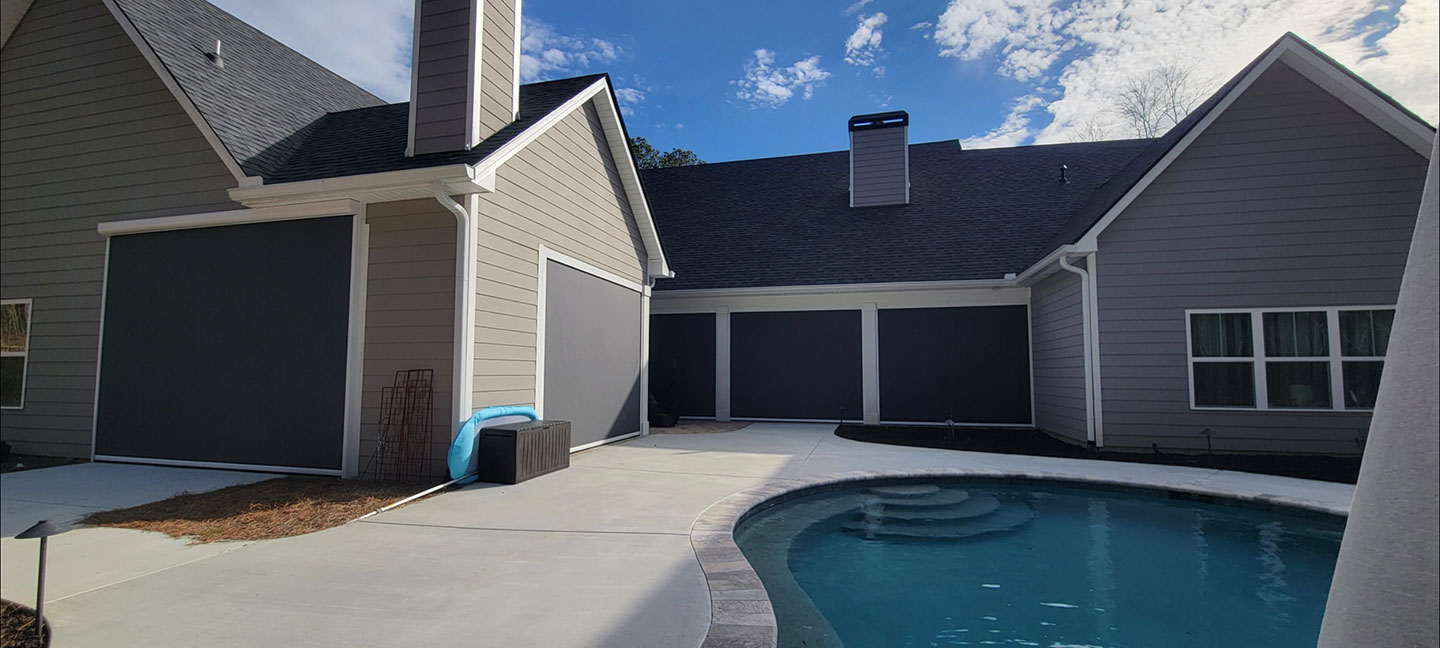 Dark outdoor shade installed across a home patio opening