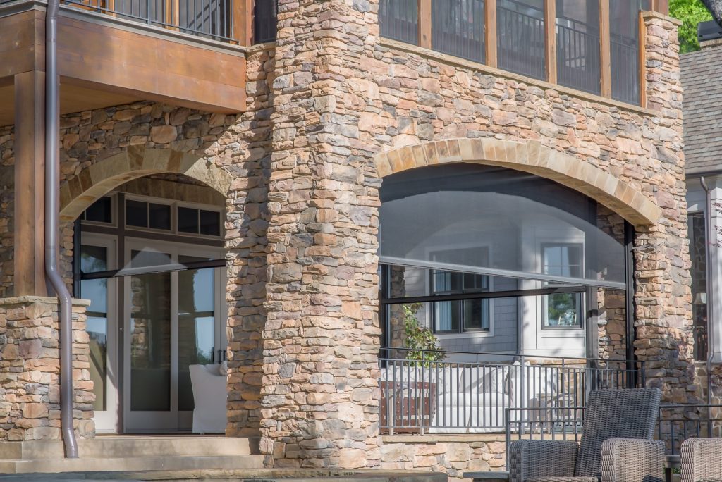 Stone home with sitting area on porch and retractable screens.